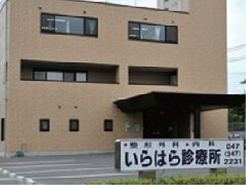 黒い字で施設名が書かれた看板が植え込みに建っている施設前