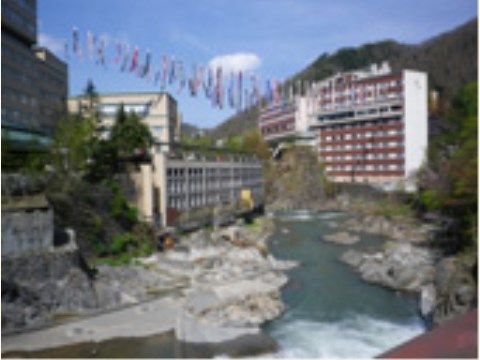清流の対岸をまたいでたくさんのこいのぼりがぶら下がっている温泉街
