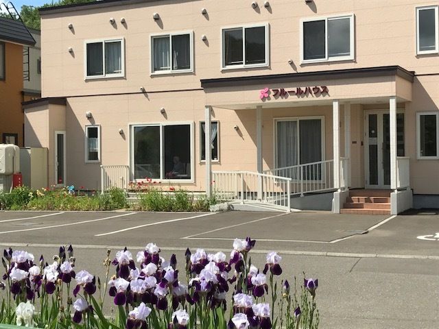 花越しに見える建物の外観。うっすらとピンク色に染まっている。