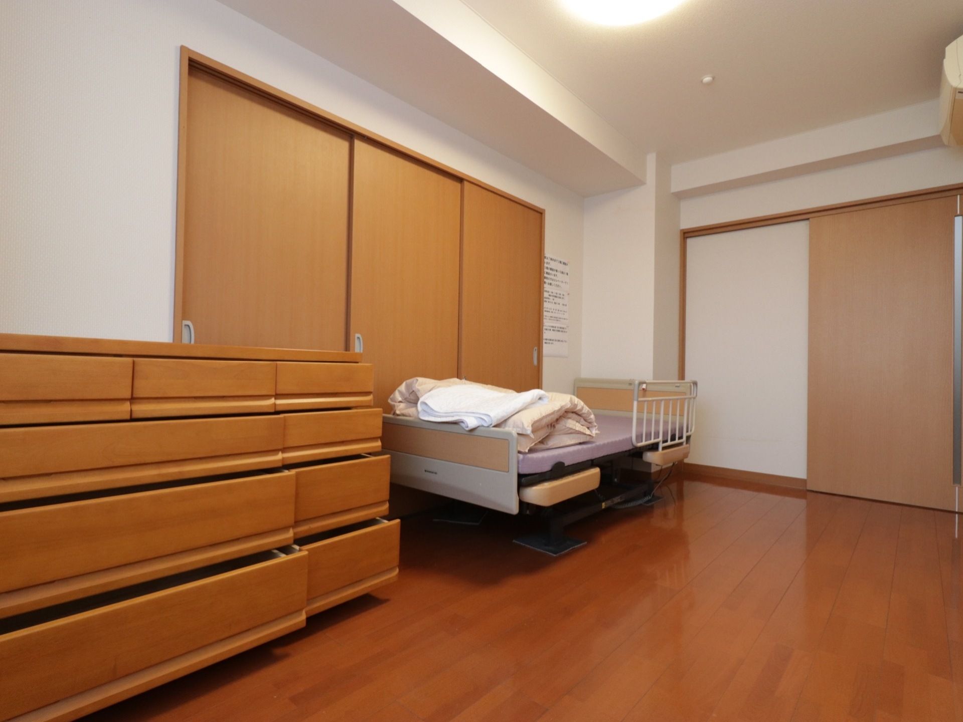 居室には明るい色の木材を多く使っている。壁際にはフェンスを取り付けたベッドと引き出し付きのチェストを置いている。