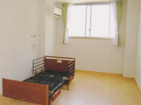 紺色のマットレスの落下防止柵付き介護ベッドが置かれた居室