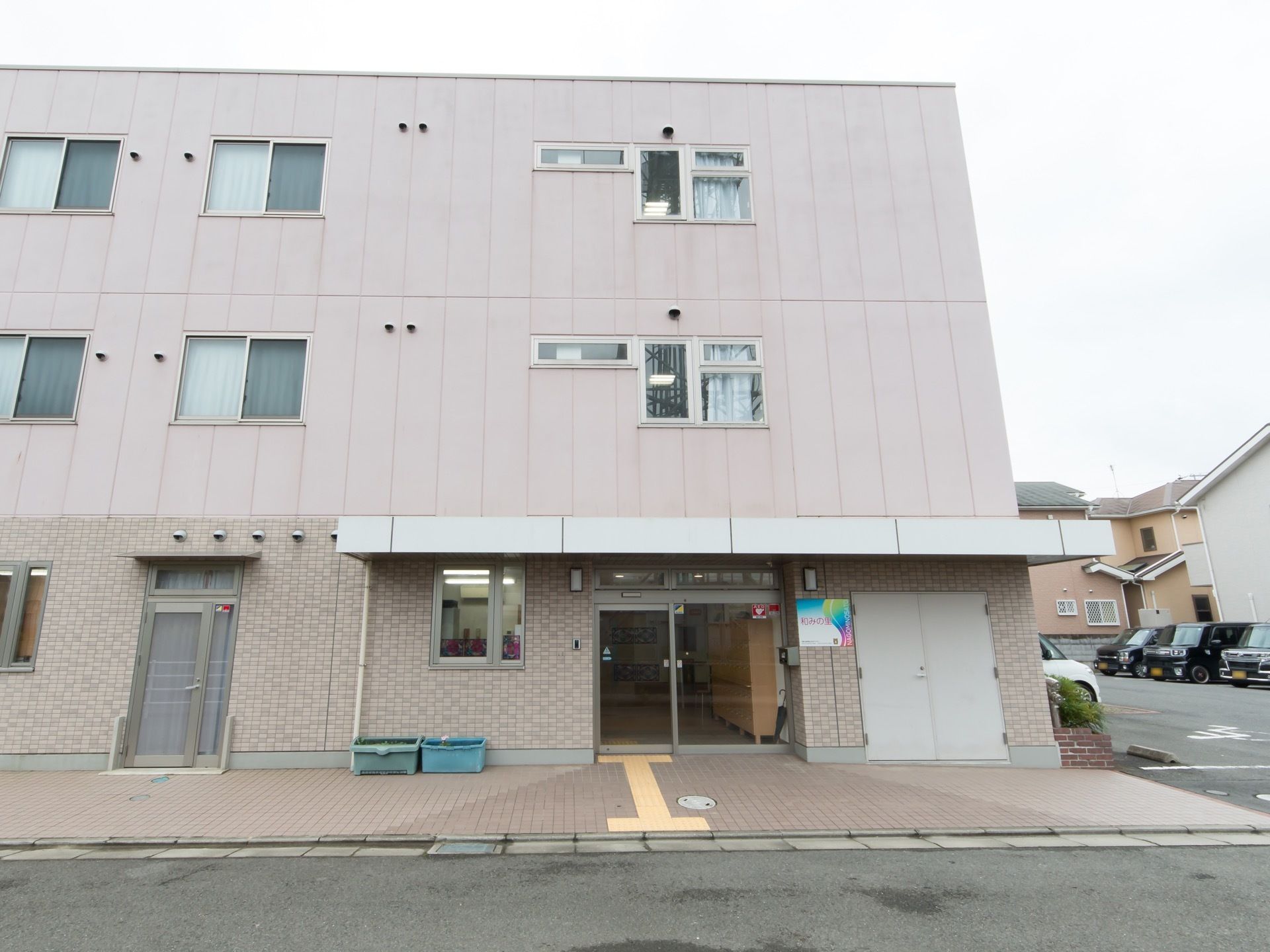 ３階建ての施設である。玄関にはガラス扉がつけられており、外から木製の収納棚が置かれているのが見える。