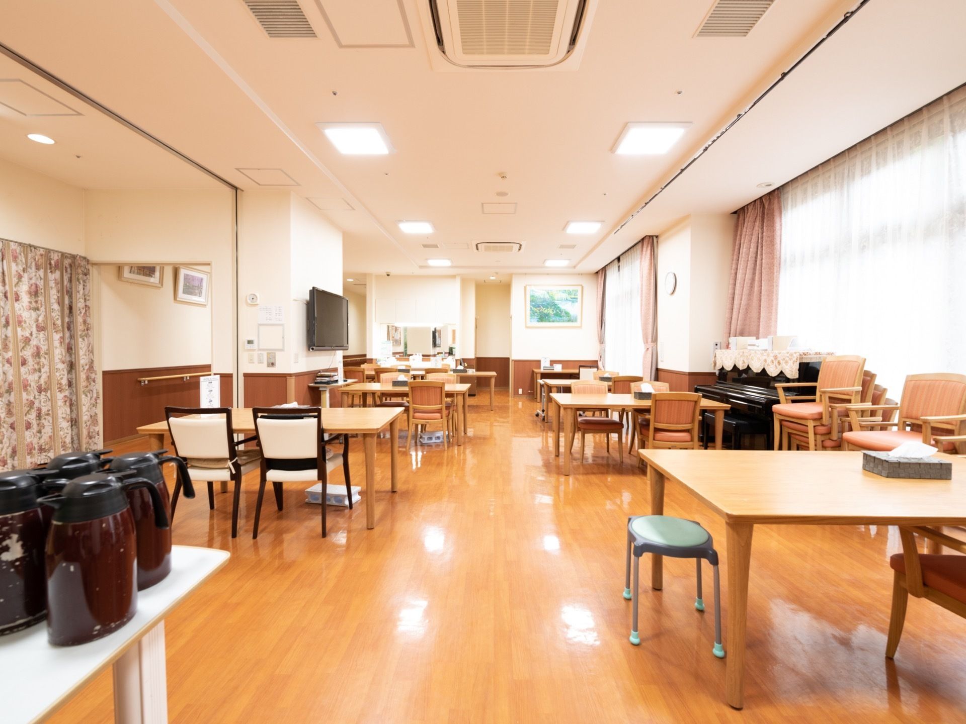 テーブルとテーブルの間が広くとられていて、ゆったりとした配置となっている。手前にある白いテーブルにえんじ色のポットが４つ乗っている。