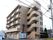 茶系の5階建の施設はマンションを改修したサービス付き高齢者向け住宅である。駐車スペースが建物の裏に設けられている。