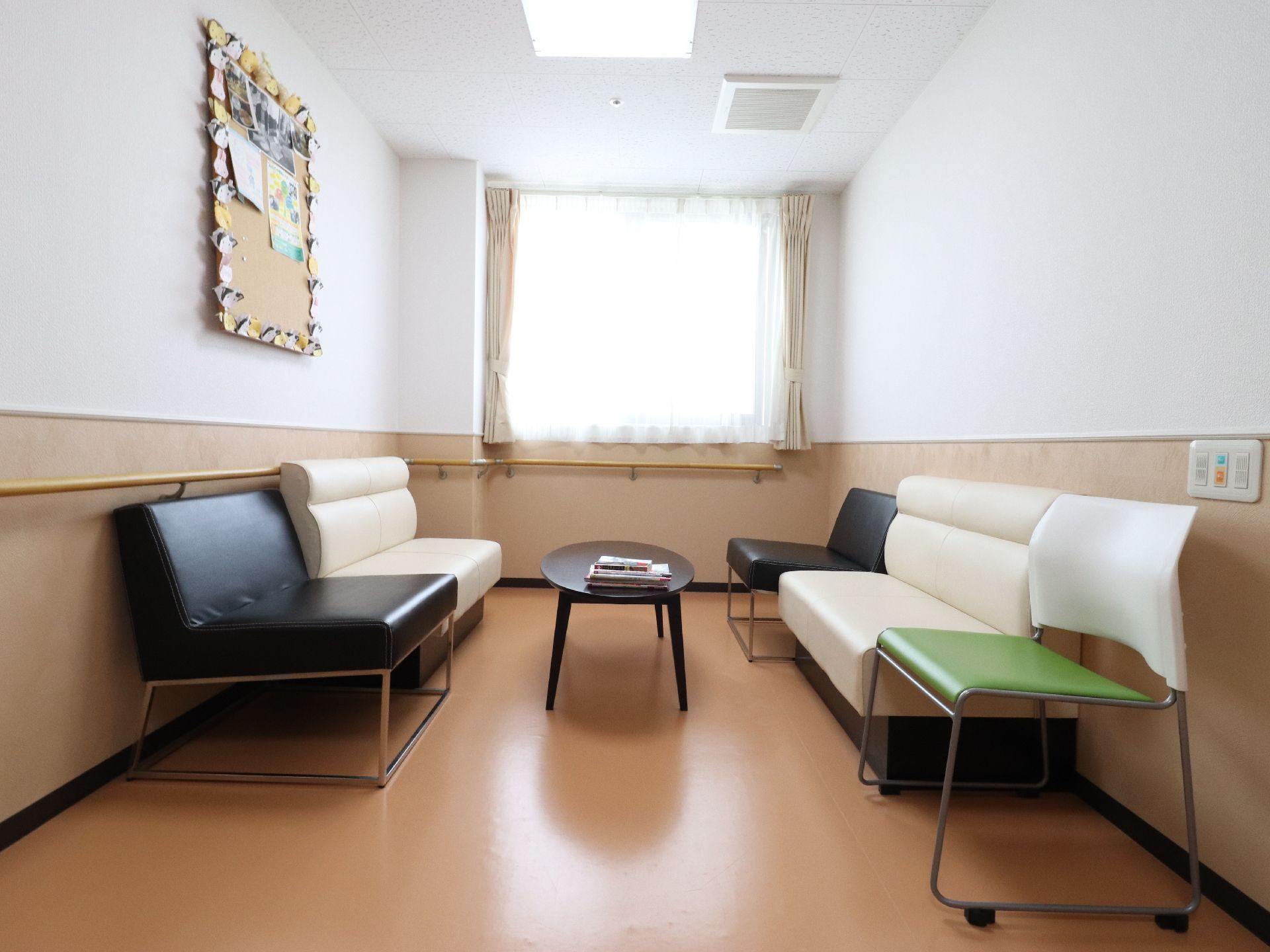 歓談室には窓があり、日が入るので明るい雰囲気である。壁には、安全に歩けるように手すりも付いている。壁には写真なども飾られている。