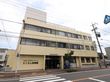 建物はクリーム色の外観の鉄筋コンクリート造3階建て。玄関横に清涼飲料水の自販機が設置されており、壁には大きく施設名が掲げられている。