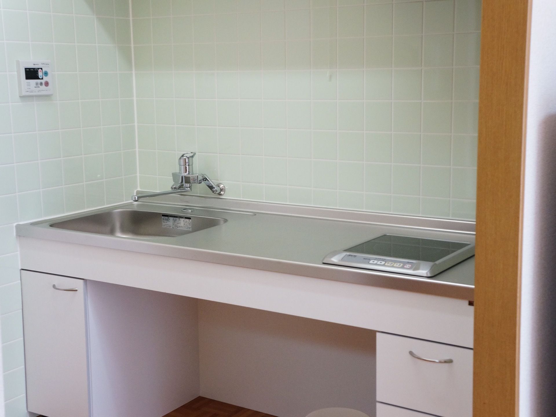 室内にキッチンが備え付けられている。シンク、調理台に電気の調理器が設置してある。収納棚の付いた便利なキッチンとなっている。