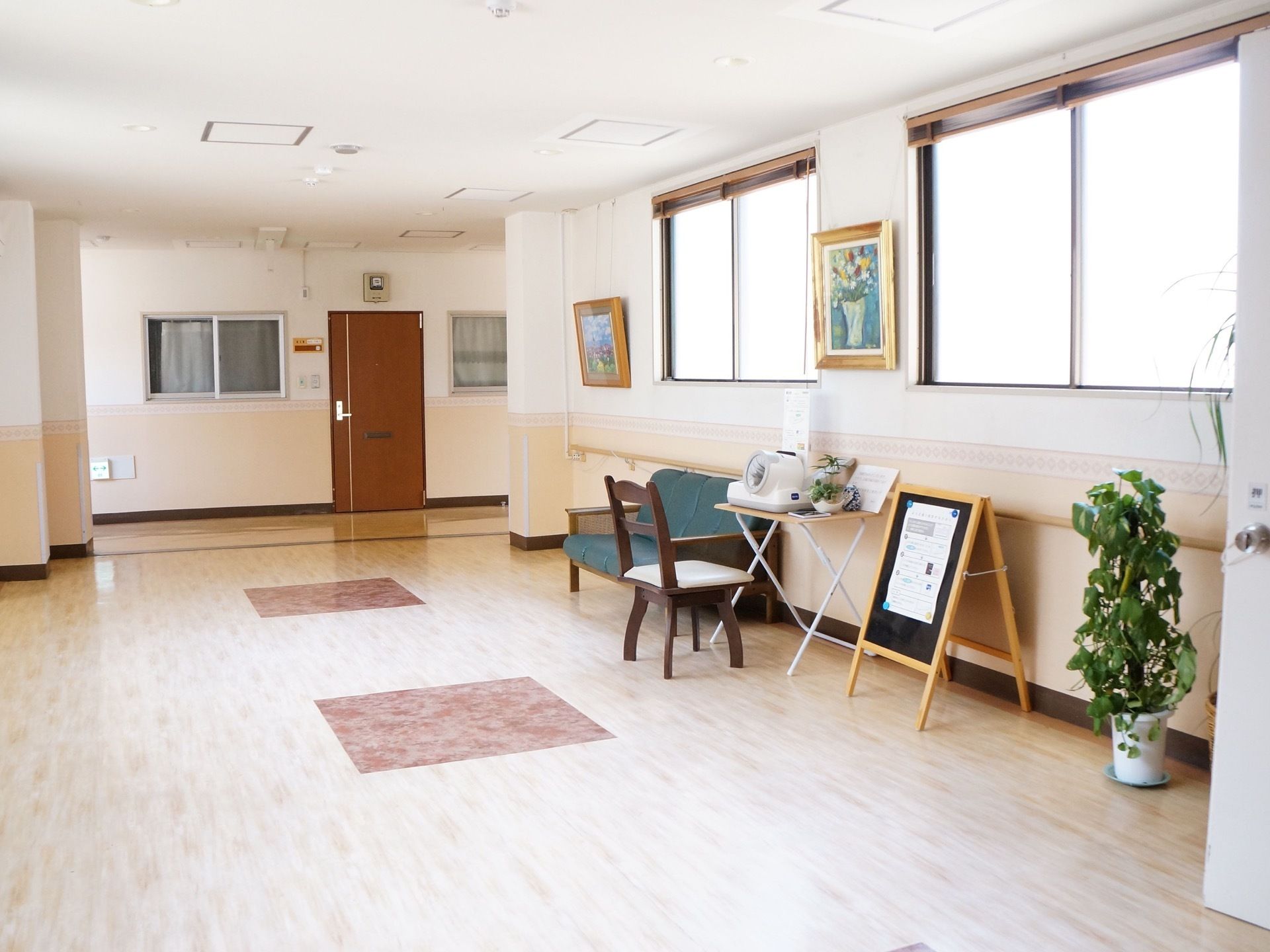 広いスペースの廊下は窓があり明るい空間となっている。ソファ、血圧計が置かれている。気軽に立ち寄れることができる場所。