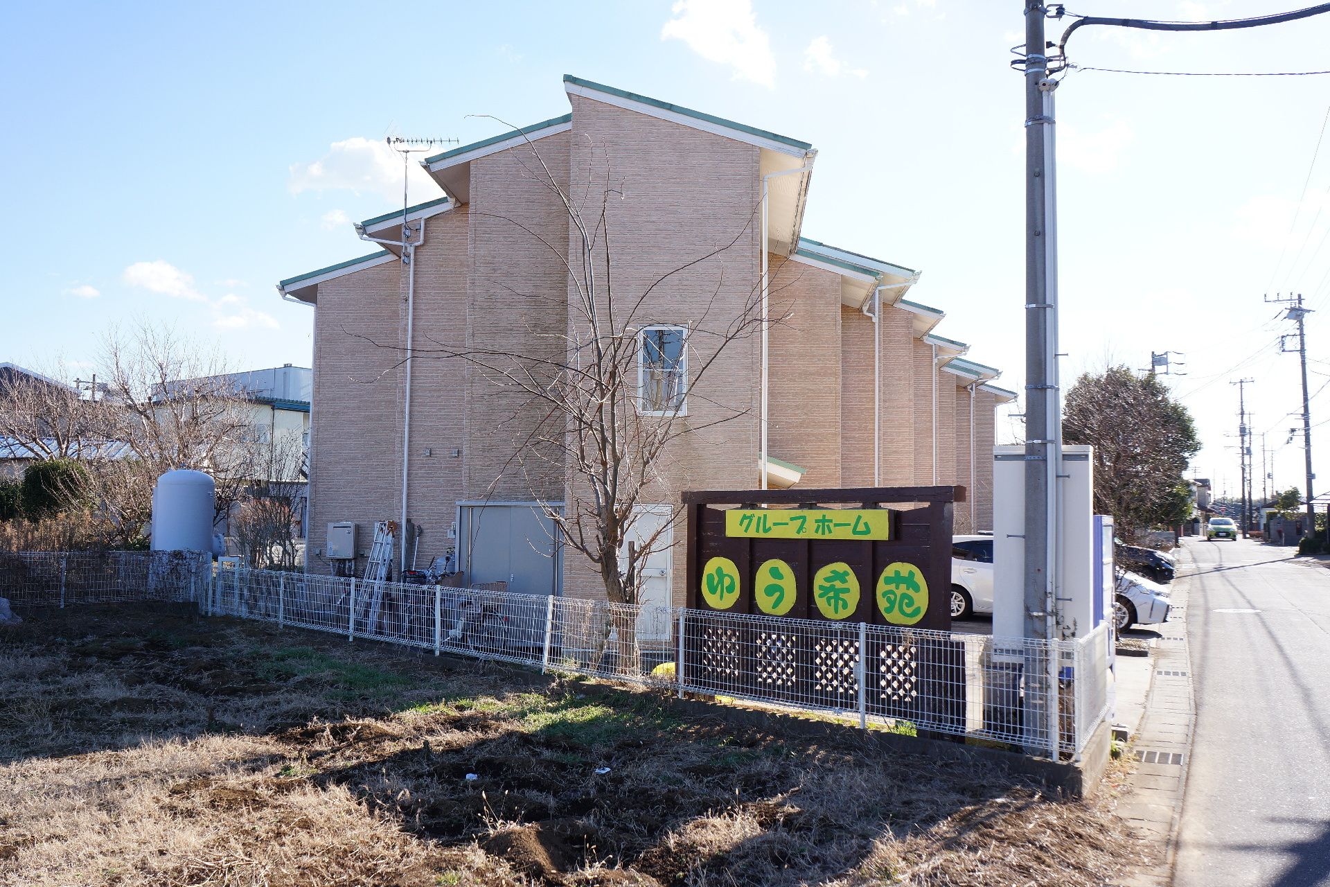 日当たりの良い環境に位置するホーム。建物前には駐車スペースが設けられている。