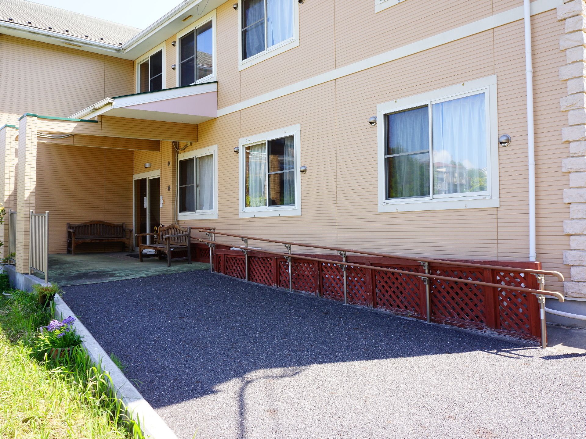 建物のアプローチはスロープ仕様になっていて、片側には、手すりが設置してある。玄関入口には屋根が付いている。