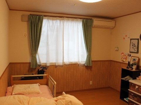 ピンクの布団が敷かれた介護用ベッドがある、フローリングの居室