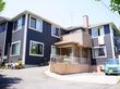 深みのあるグレー色の外壁に茶系でまとめられたエントランスの鉄骨造2階建の建物。屋根には煙突が設置してある。
