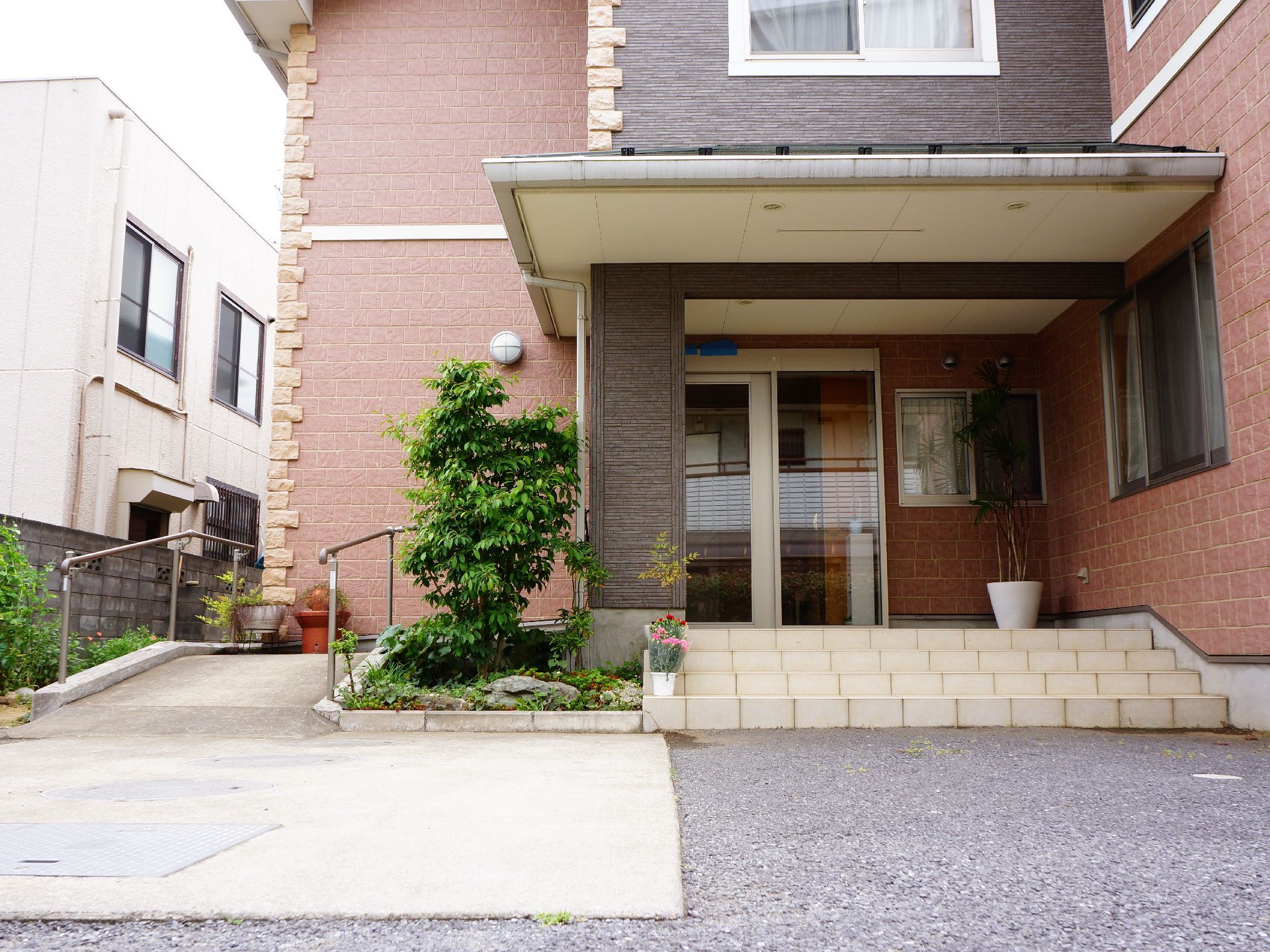 施設エントランスを正面から見たところ。玄関は銀色の枠を持つガラス張りの自動ドアになっていて、脇には受付がある。
