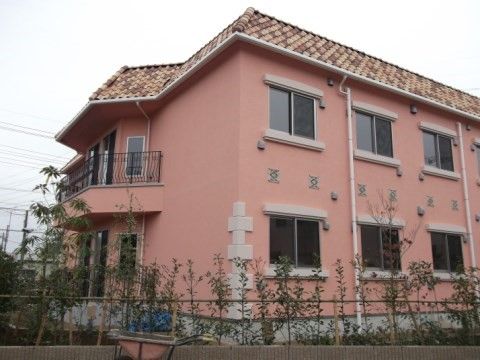 植えられたばかりの若い樹木で囲まれたピンク色の建物