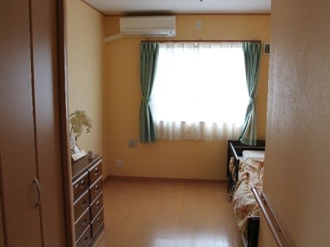 左側に天井まで届くクローゼットと、木製のチェストがある居室