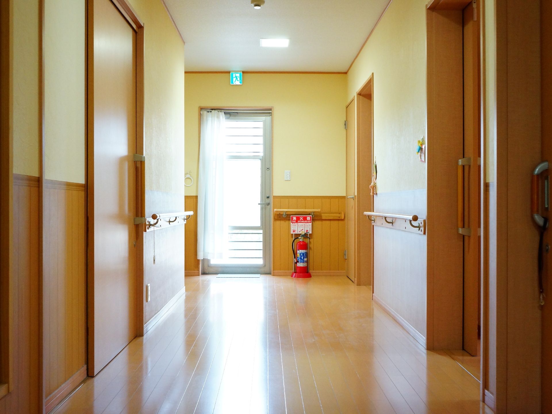 窓から自然の光が差し込む廊下。転倒防止用の手すりが通路の両側についているため、安全に施設内を移動できる。