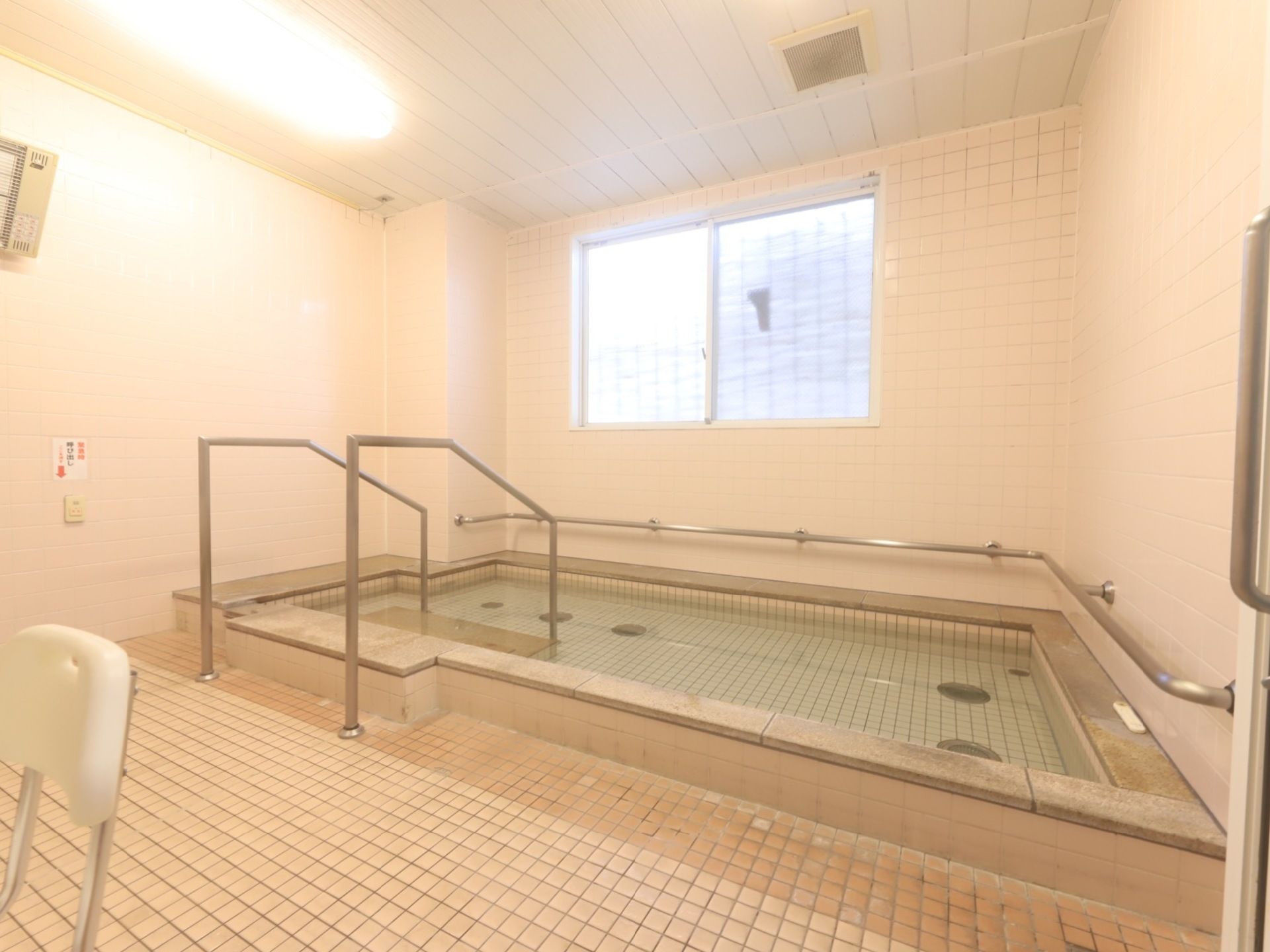 大浴場には窓があり室内換気を気軽に行うことができる。手すりが備わっている。白で統一された明るい空間である。