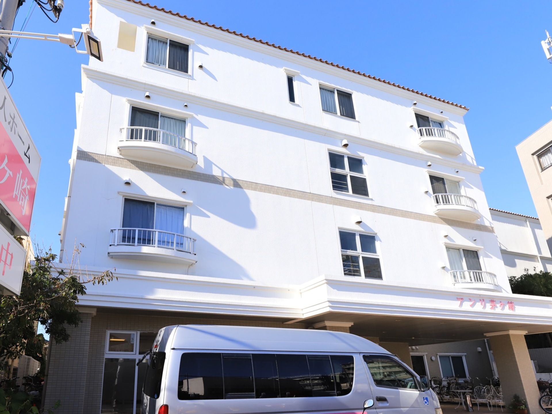 ４階建ての建造物で、周辺に視界を遮る大きな建物がなく日当たりに恵まれている。玄関先に施設車が止まっている。
