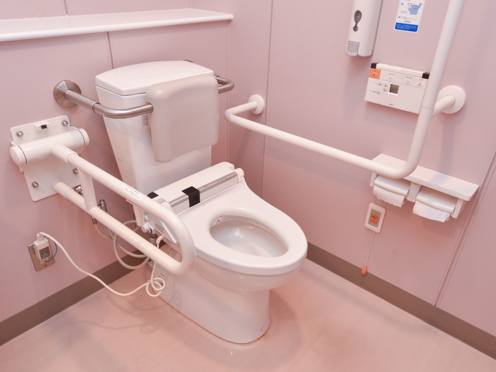 トイレの様子である。可動式の手すりや呼び出しボタンが付いていて安心安全である。背もたれも付いている。