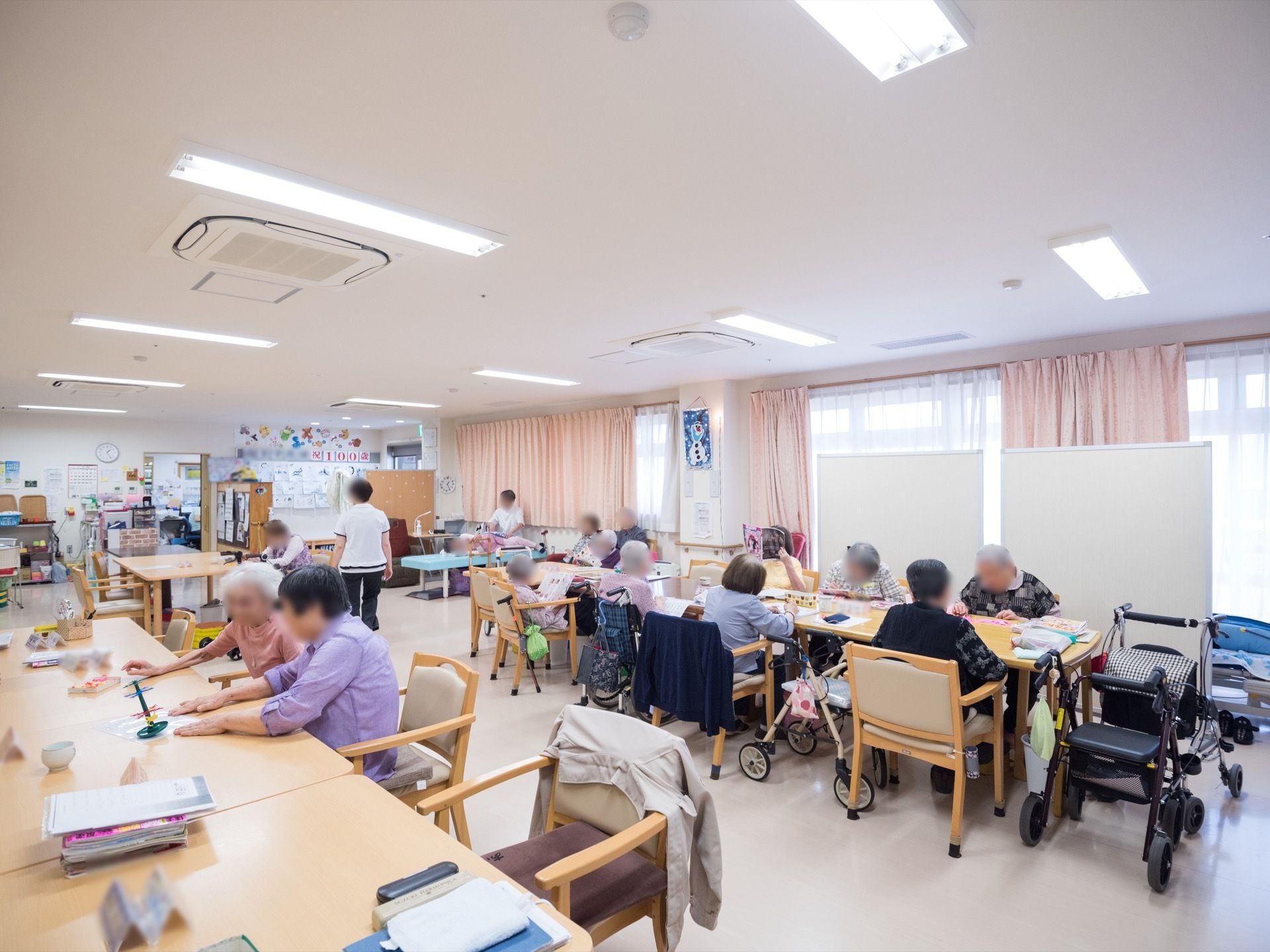 室内は広々としていて、日当たりが良く居心地の良い雰囲気になっている。テーブルが部屋の中央に並べられ、入居者様が一堂に集まって過ごせる。