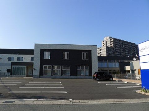 ２階建ての施設の前にある、乗用車が１台停まっている駐車場