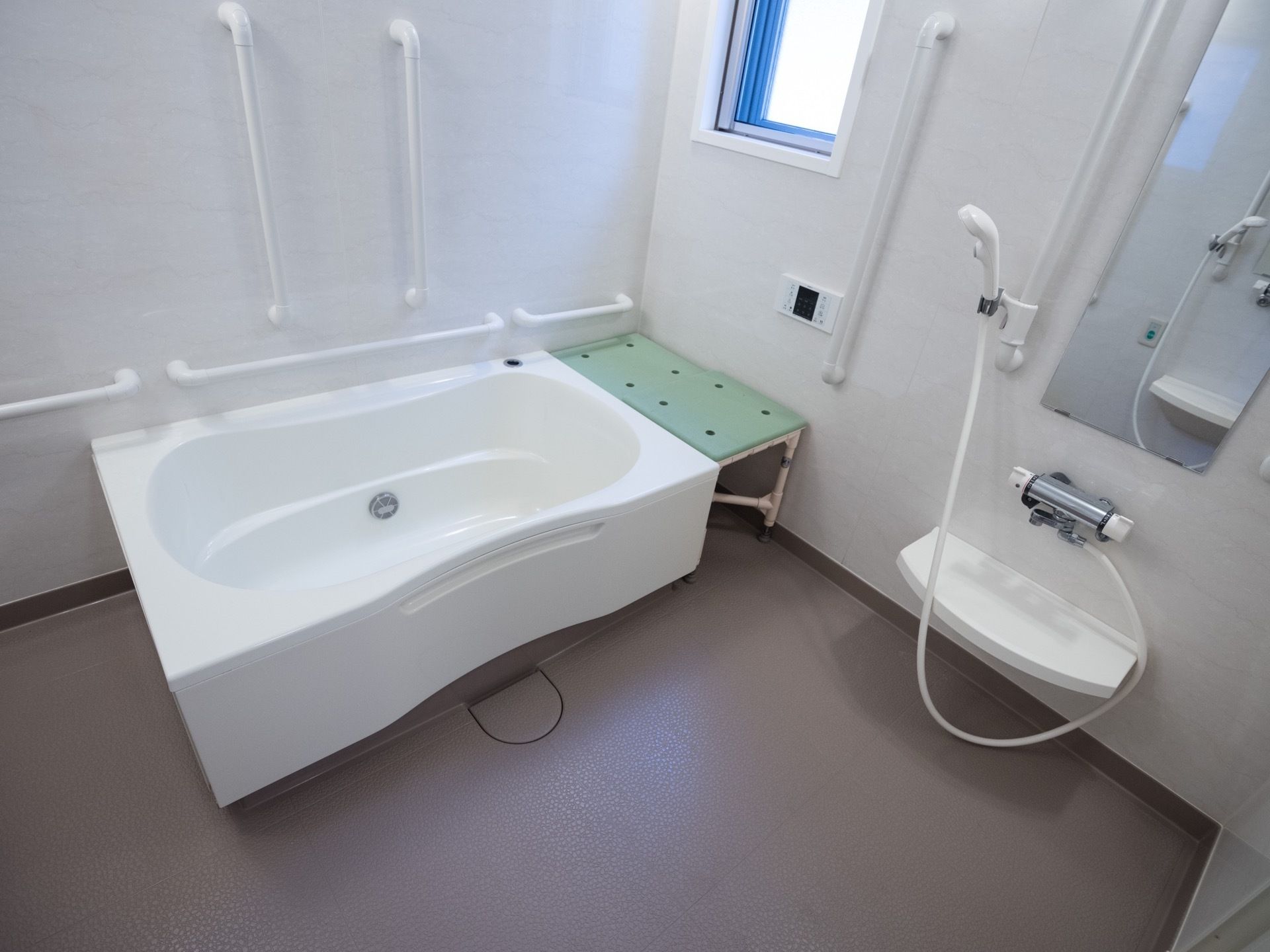 浴室は広々としている。洗い場と浴槽に分かれており、壁には縦型と横型の手すりが取り付けられている。洗い場には鏡も設置されている。