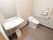 トイレの左側に洗面台があり、壁には鏡が設置されている。足元には白い縦長の四角型のゴミ箱が置かれている。