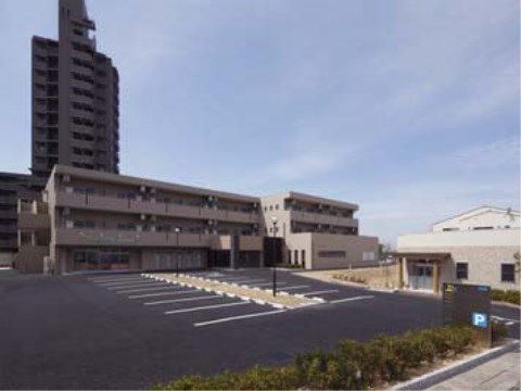 「プレステージ小幡緑地」の外観。住宅街と高速道路寄りに位置し、3階建てこげ茶色のタイル張りの外観。
