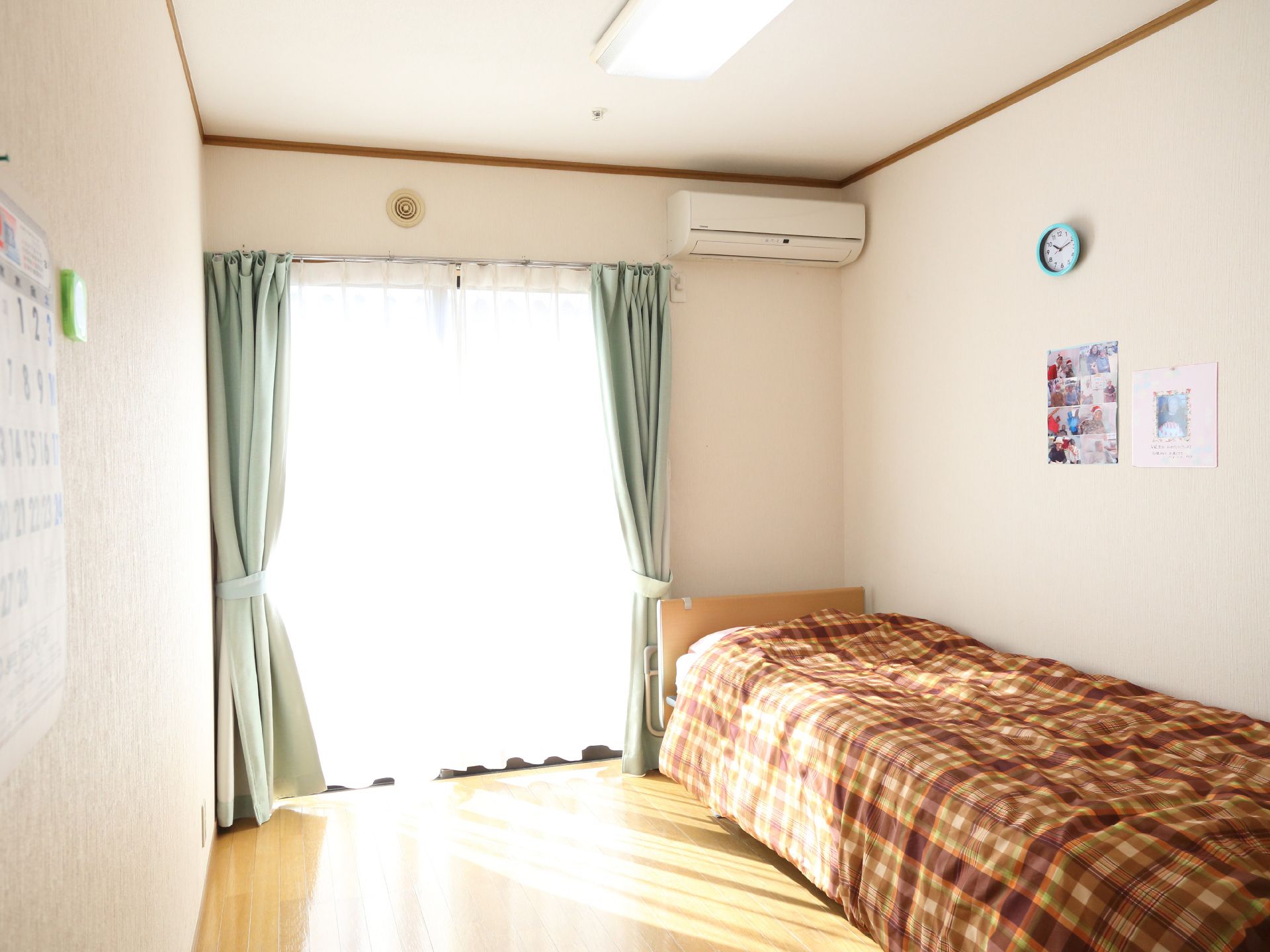 茶色とオレンジのチェックの布団が敷かれたベッドがある居室