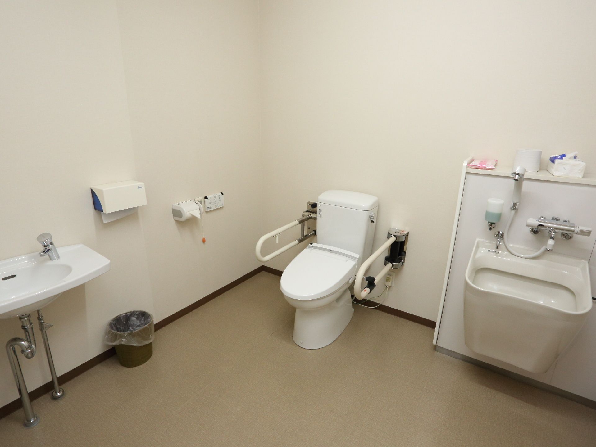 トイレと洗い場台が一緒になっている。手すり、温水洗浄機能付き便座、ナースコールがあり、広いので車椅子のまま入れる。