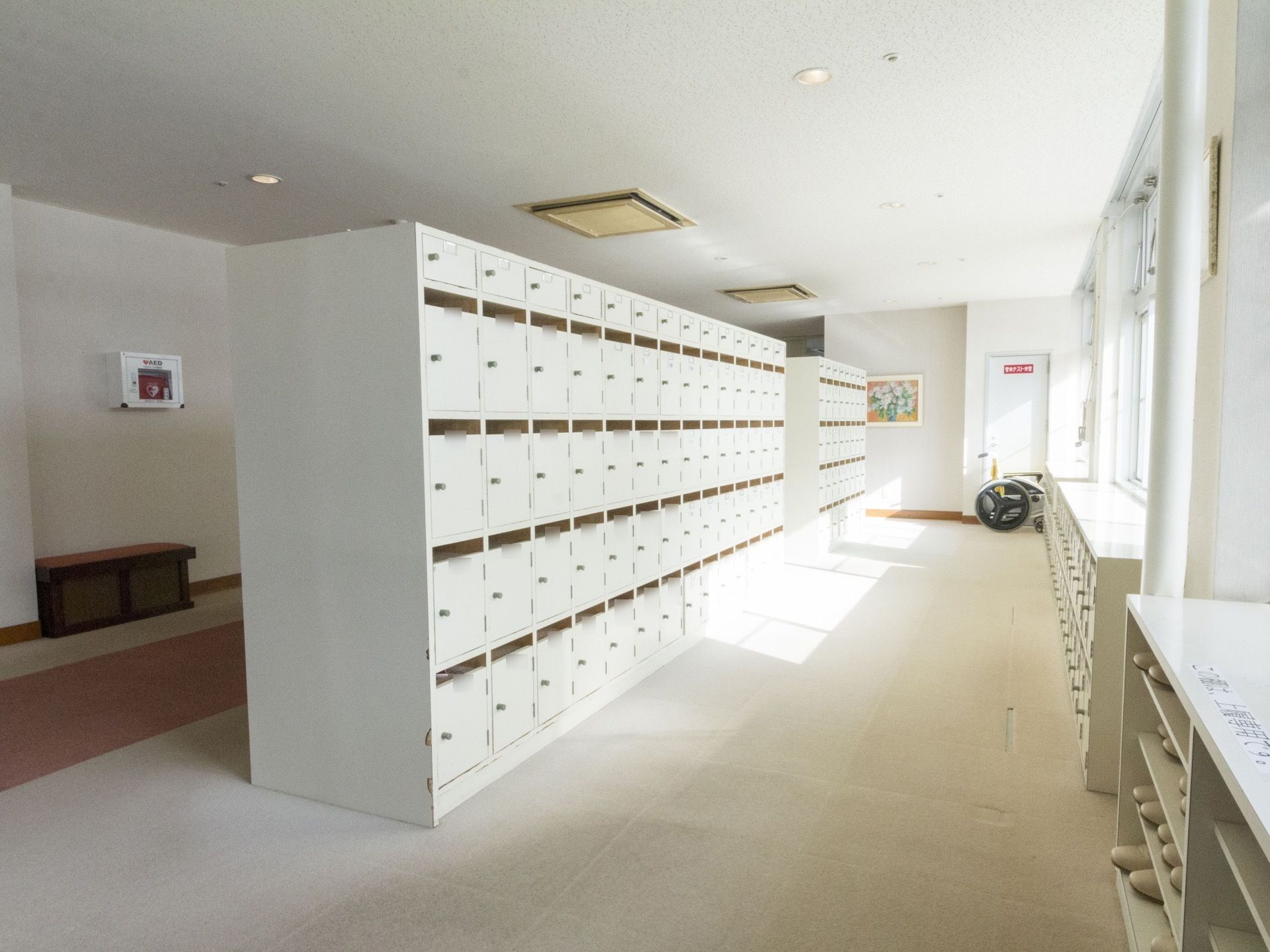 靴箱、天井、壁、絨毯全てが白で統一されており、上品で清潔感のある空間となっている。靴箱には入居者様のお名前が記されており見分けやすい。