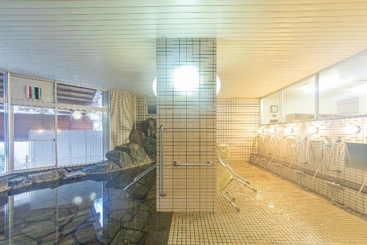 浴槽の床には滑りにくく、雰囲気のある石が敷かれている。外の植栽が目の保養になり、ちょうど良い目隠しにもなっている。