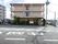 道路越しに見た施設。２階から上のベランダは建物の全周を囲う形になっている。正門は右寄りに設けられている。