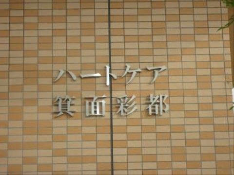 オレンジとベージュのレンガ造りの壁に設置されたステンレス製の施設名