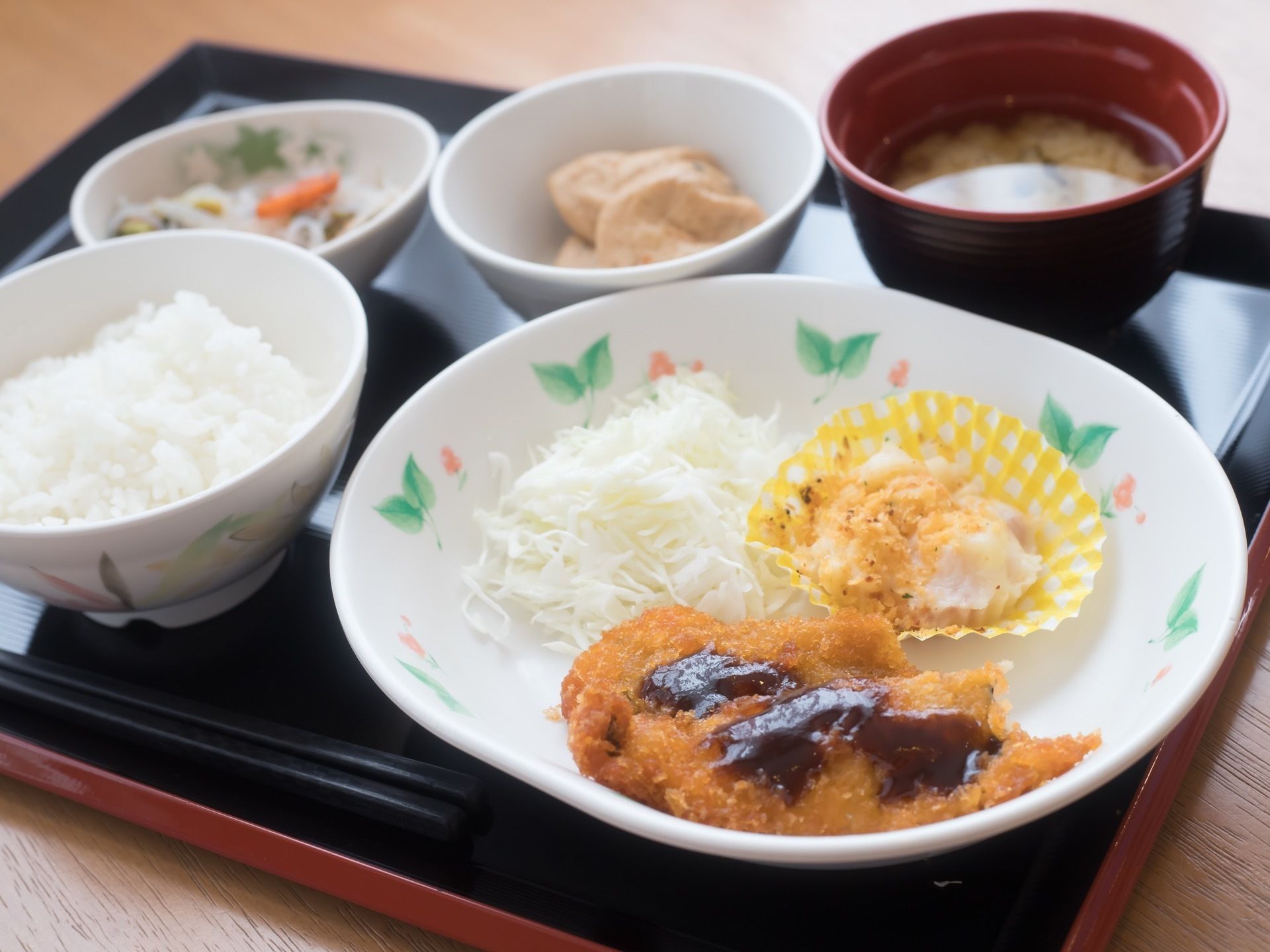 黒いトレーの上に一食分の食事が置かれている。ご飯と汁物、メイン料理の揚げ物と副菜２品が並べられている。
