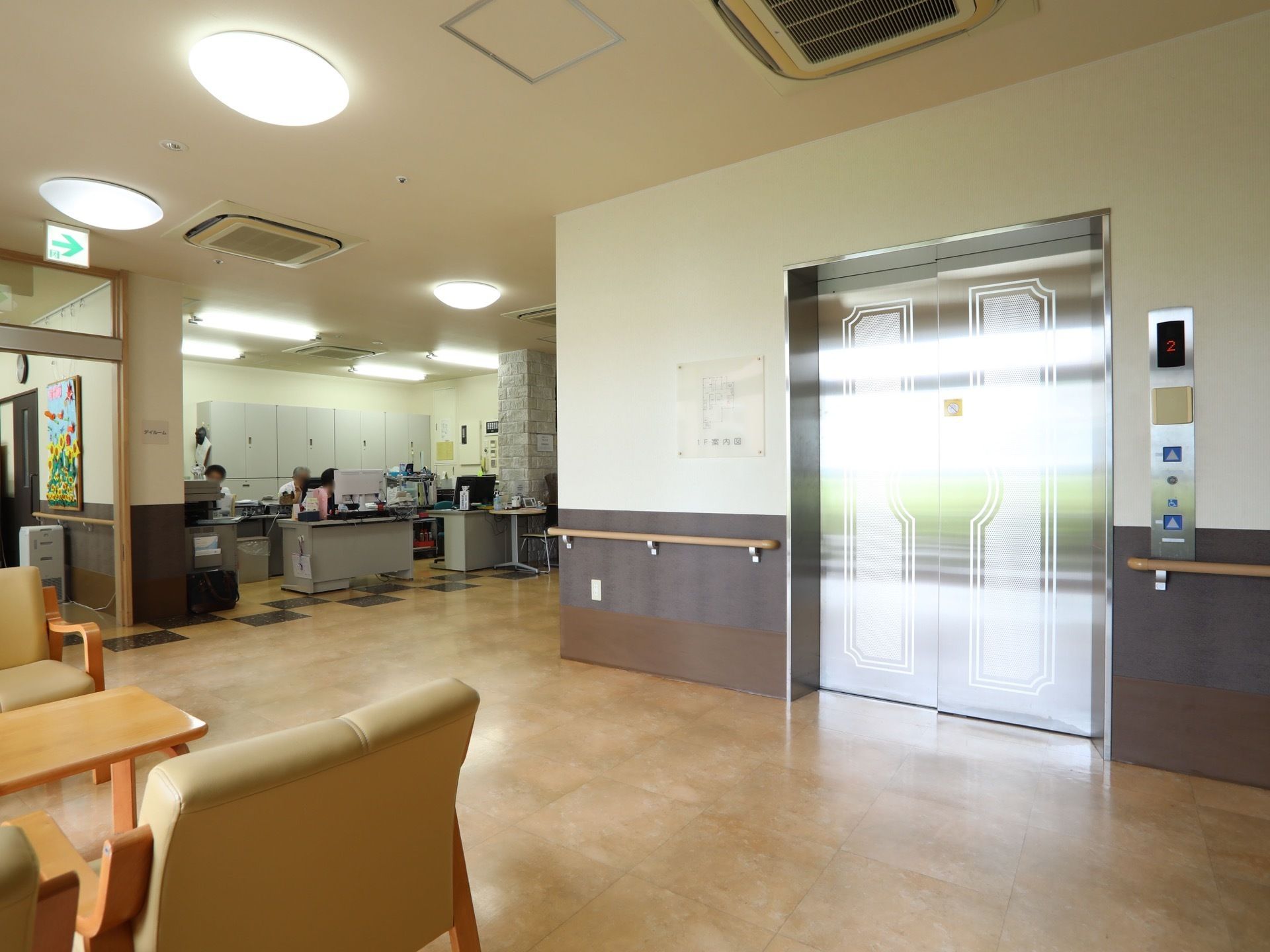エレベーターが１基設置されており、左右両側の壁に手すりがかかっている。手前のフロアにテーブル席を用意。