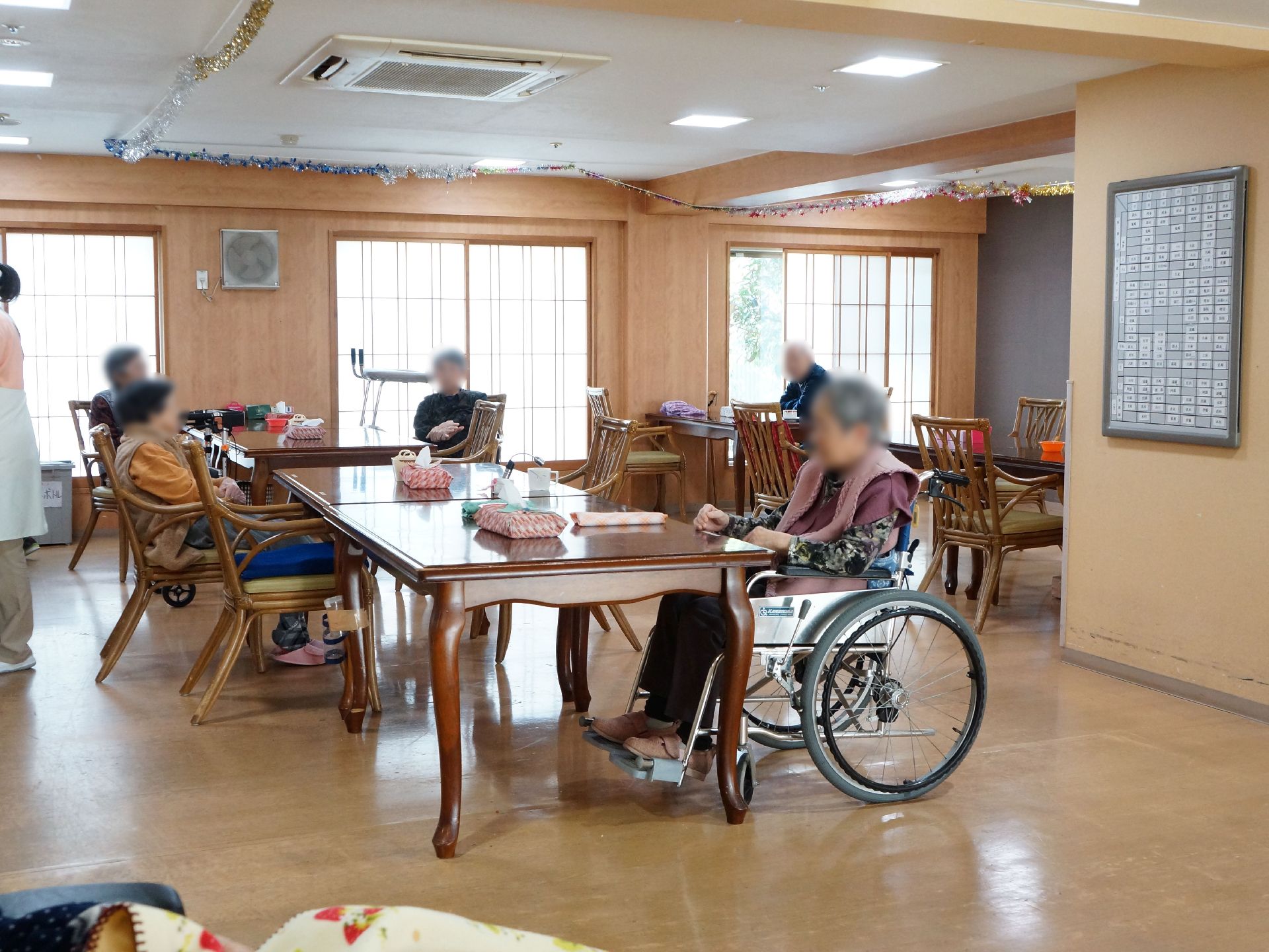 テーブルと椅子が幾つも配置されている。窓は多く障子が付いている。壁には換気扇があり、天井にはエアコンがある。