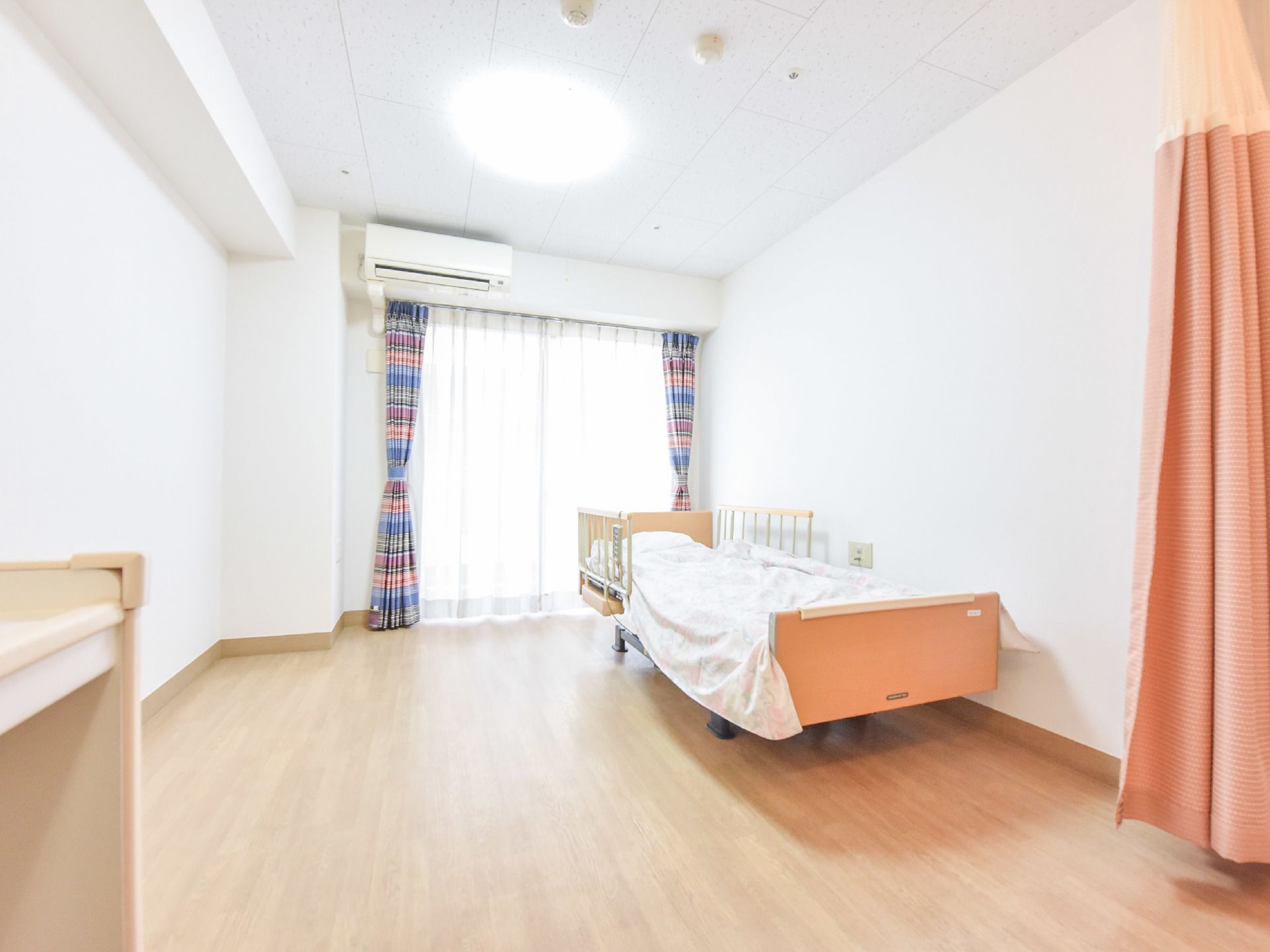 個室にはシングルサイズのベッドが置かれている。電動式のベッドであり、周りに柵がついている。窓もあり日当たりが良い。