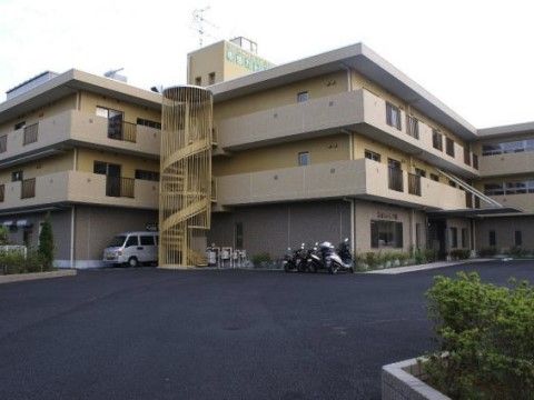 らせん状の外階段がある、ベージュ色の３階建ての施設