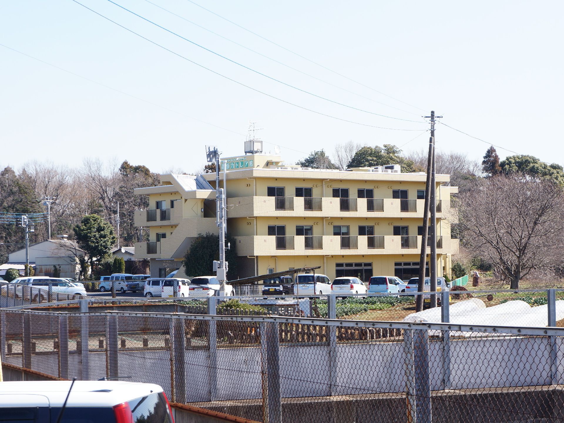 施設はアイボリーの3階建ての建物。周りには木が多く、近隣に高い建物はない。閑静な場所に立地している。