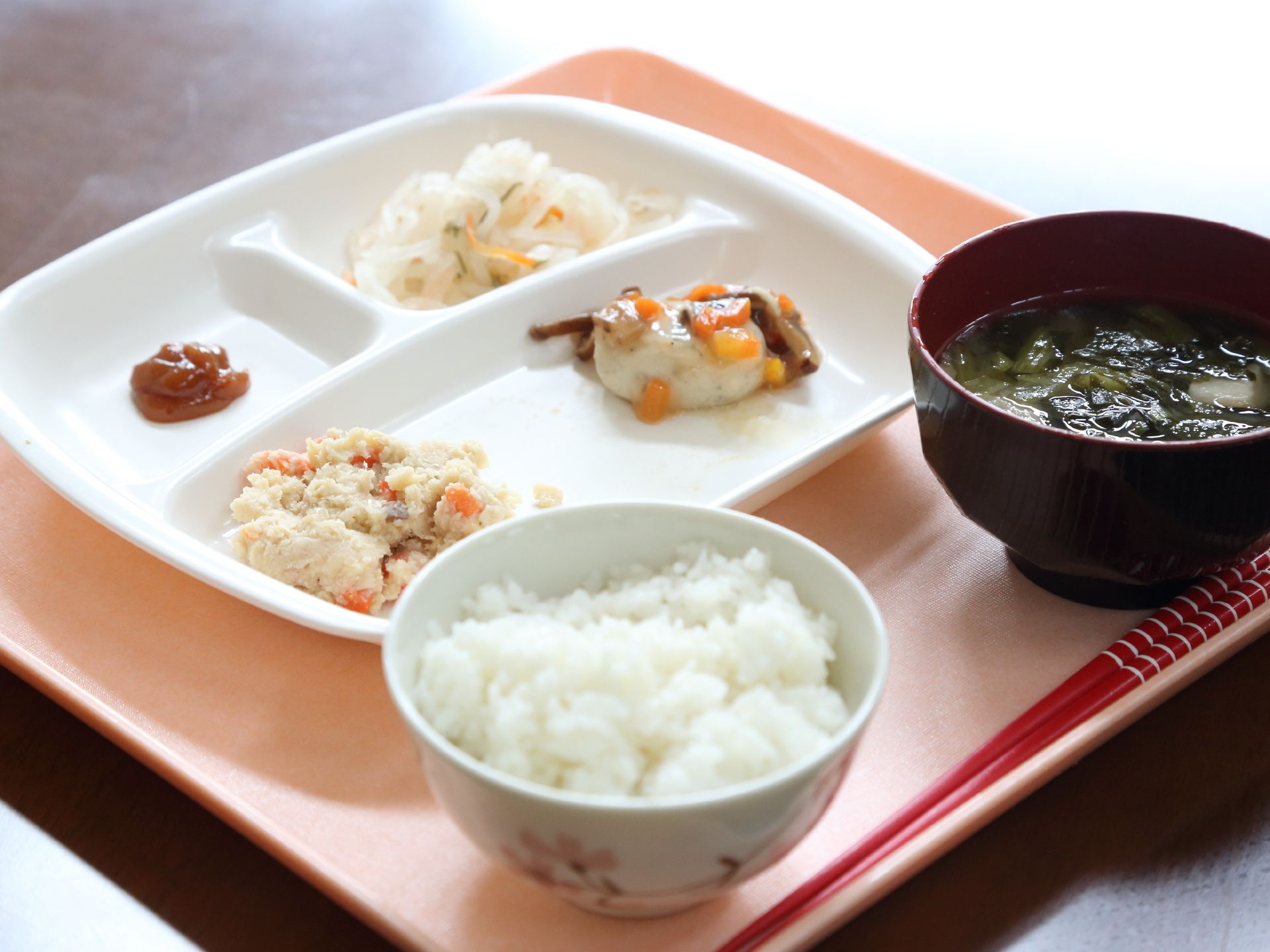 オレンジ色のトレイに配膳されたおからやなます、ごはんとみそ汁