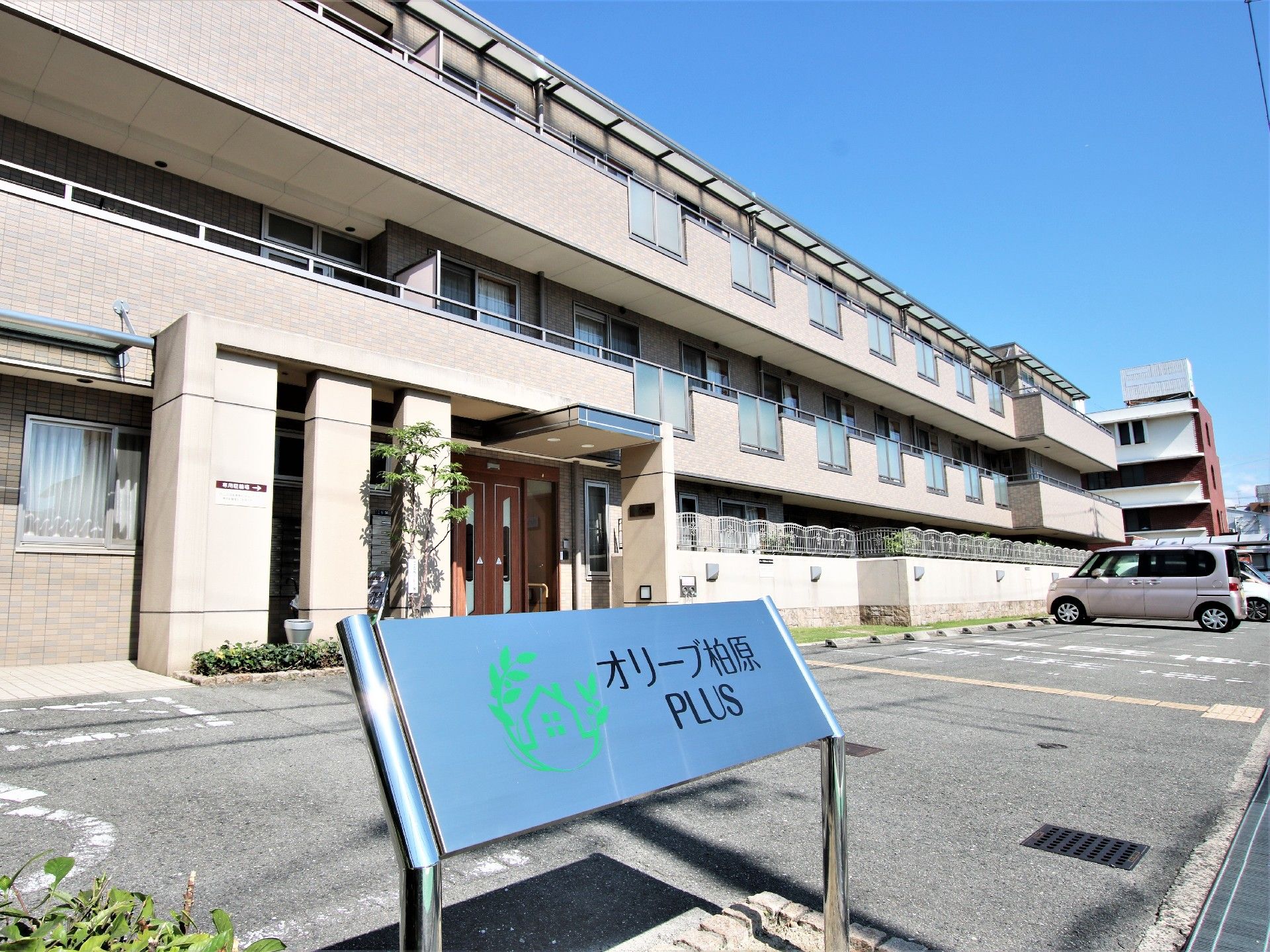 ステンレス板に施設名が書かれた看板が立つ施設の玄関前