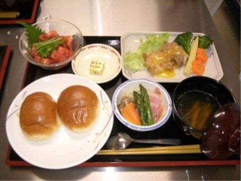 マーガリンが添えられたロールパンが２つ、トマトのマリネが並ぶ食事