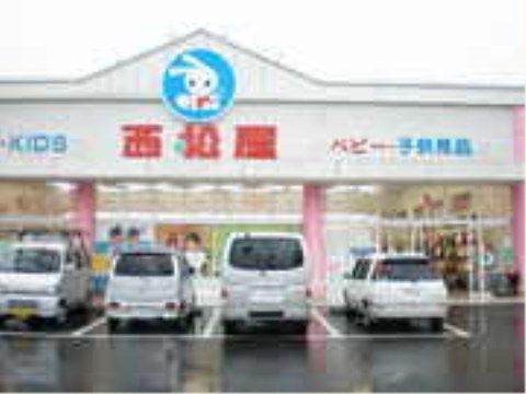 ベビー・子供用品店の店舗の正面外観である。平屋建ての建物であり、屋根には店名が表示されている。店舗の前には駐車場が設けられている。