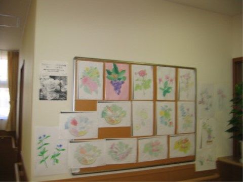 入居者様が書いた花の絵などが飾られている廊下の掲示板