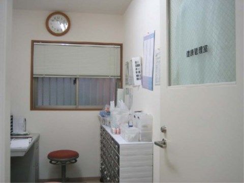 赤いクッションの丸椅子が置かれたデスクがある健康管理室