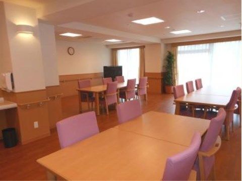 「ニチイケアセンター横浜戸塚」のダイニング兼機能訓練室。目に優しい照明と日差しで心安らぐアットホームなダイニング空間である。