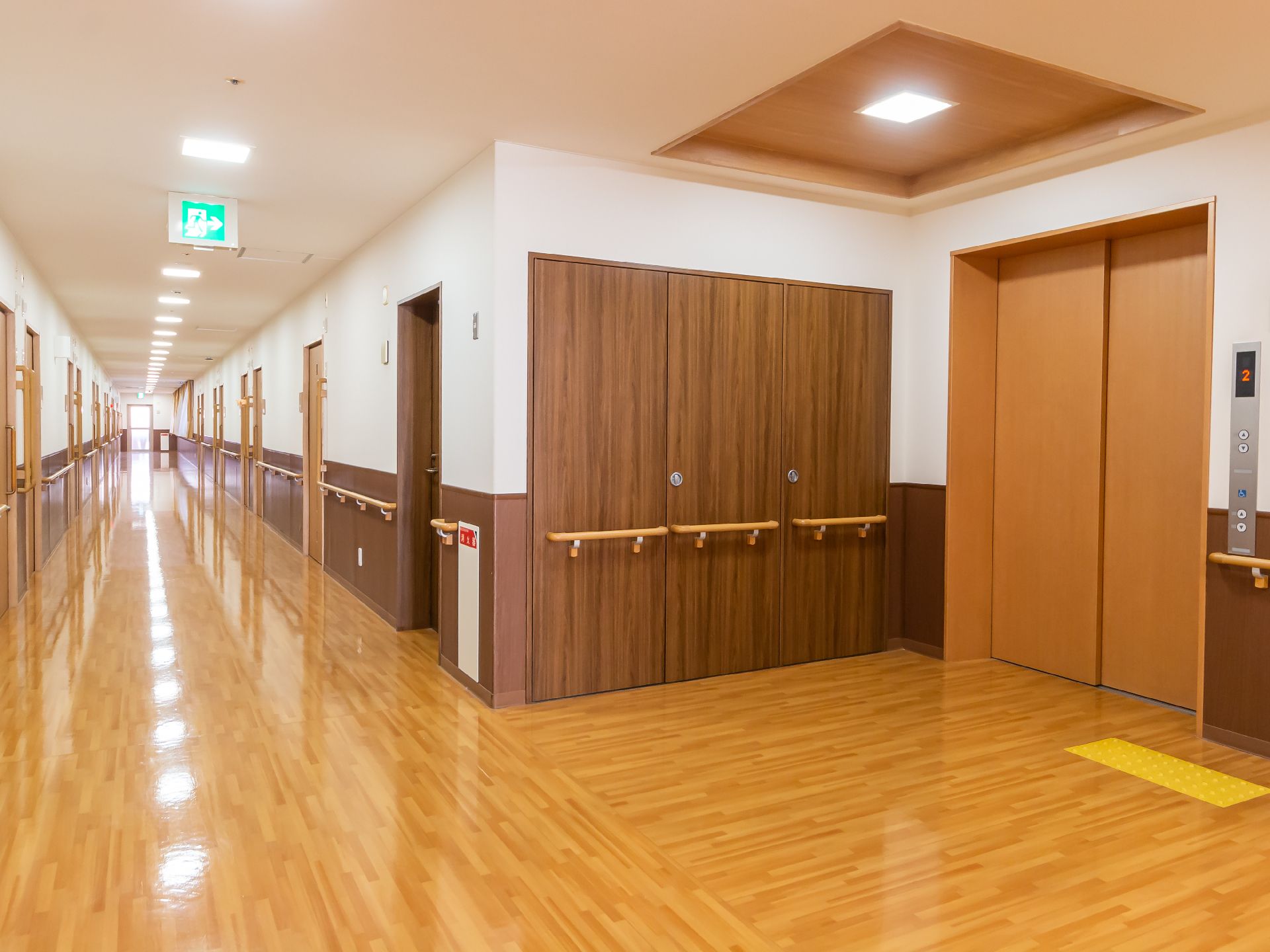 手すりが取り付けられ、黄色い壁に絵が飾られている廊下