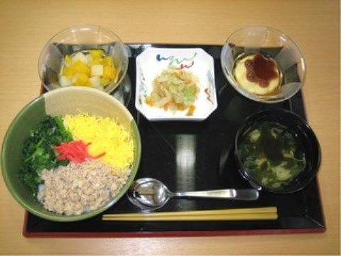 お箸やスプーンと一緒に黒いプレートに並べられている丼物が主食の献立