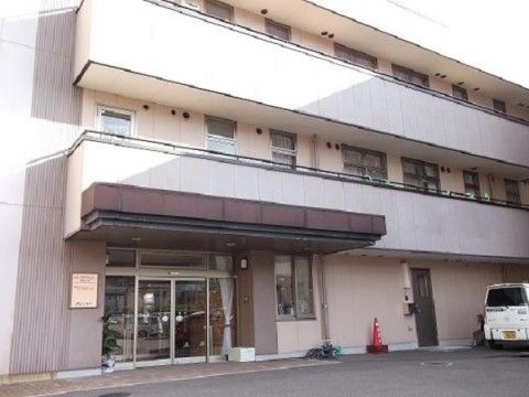 「ニチイケアセンター周南久米」の外観。森と田んぼと住宅に鉄骨造3階建ての施設で、バリアフリーのエントランスになっている。